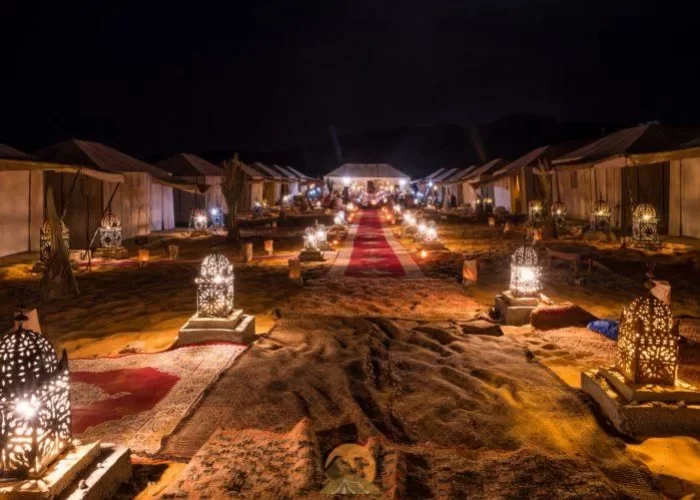 A group of tents with lights in the middle of Luxurious Camps in the Middle of the Sahara Desert