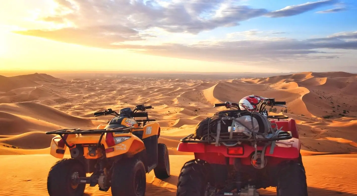 Two quad bikes parked in the desert, silhouetted against a vibrant sunset sky :Quads in Erg Chebbi