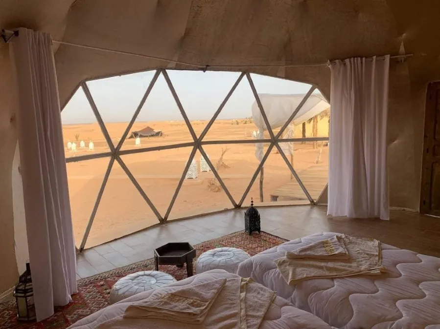 Two beds inside a tent, offering a scenic view of the expansive desert landscape outside.