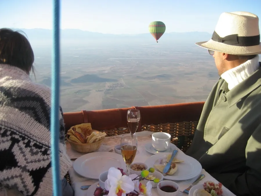 A man and woman engaged in conversation while seated at a table enjoying  Moroccan Balloon Ride Over the Desert