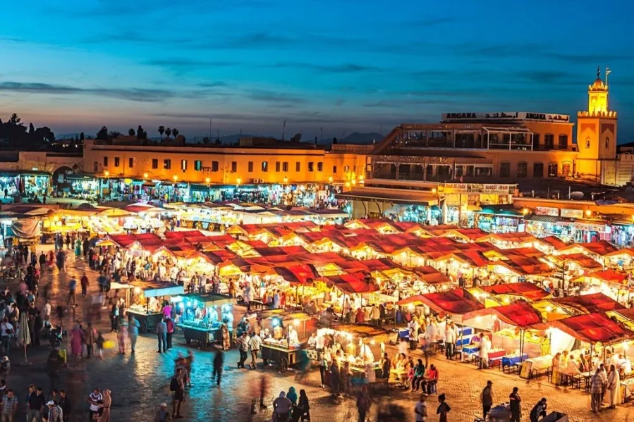 Marrakech skyline at dusk, showcasing vibrant colors and illuminated buildings against a twilight sky.