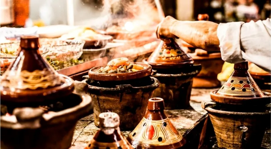 A man is preparing a meal in a pot placed on a table, focused on his cooking process.